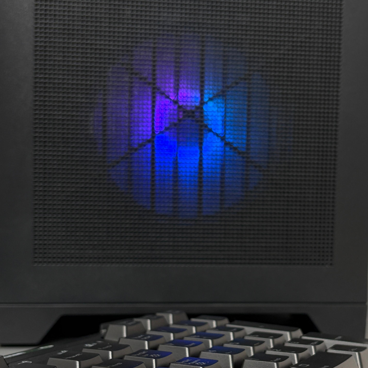 Close-up of a computer case with a blue LED light and keyboard in front